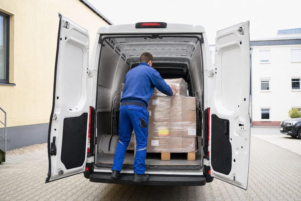 Fahrer verlädt eine Palette in einen weißen Transporter